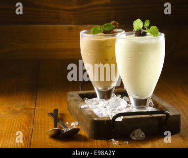 Deux de délicieux milk-shakes icecream épais garnis de chocolat et menthe et servi dans de grands verres réfrigérés sur un petit plateau de bois vieux Banque D'Images