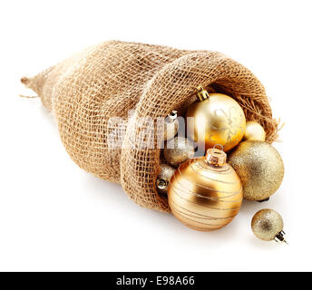 Variété de boules de Noël en or d'ornement dans un sac de jute débordant sur un fond studio blanc Banque D'Images