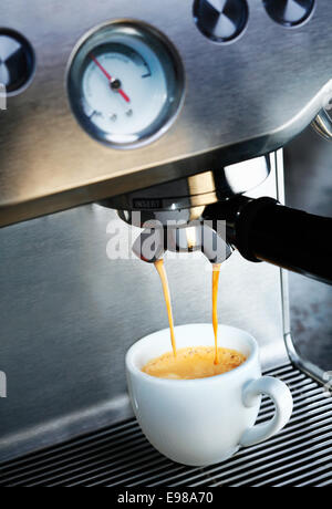 Machine à café filtre automatique dispense une délicieuse tasse de café aromatique moussé chaud dans une tasse en céramique blanche d'une restauration Banque D'Images