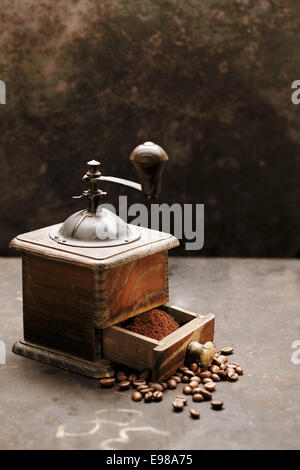 Ancien moulin à café en bois rustique sur une surface en ardoise avec des grains de café torréfiés et en poudre dans le tiroir Banque D'Images