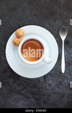 Vue de dessus de strong mousse café expresso dans une tasse et soucoupe avec deux macarons traditionnels et une cuillère à café d'argent Banque D'Images