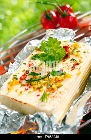 Une délicieuse portion de fromage feta ou halloumi surmontée de fines herbes et épices grillées sur un barbecue en plein air Banque D'Images