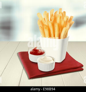 De pommes de terre frites croustillantes des matraques ou des jetons debout dans un récipient en céramique blanche avec une portion de ketchup et de la mayonnaise de ramequins individuels sur une serviette rouge sur le comptoir