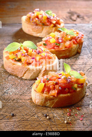 La préparation de délicieux bruschetta Italienne, un petit apéritif sur pain grillé crisp, avec plusieurs préparé tomates bruschetta sur Banque D'Images