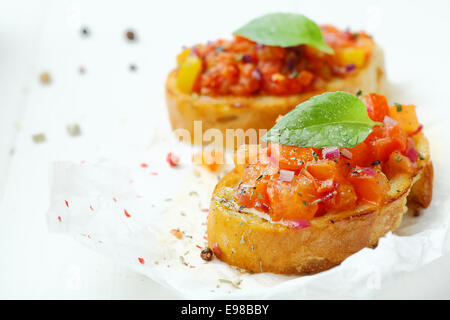 Baguette garnie bruschetta à la tomate et oignon topping sur grunge paper tachés de sauce et assaisonnements Banque D'Images