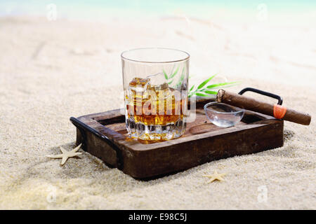 Belle image de scotch sur les rochers dans un plateau en bois sur une plage de sable. Banque D'Images