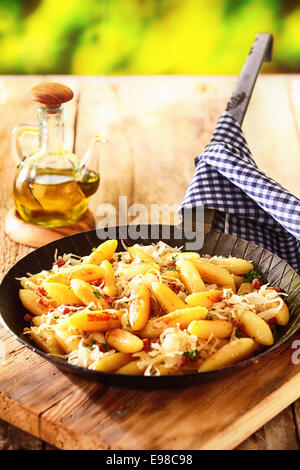 L'allemand de nouilles et boulettes de pommes de terre en forme de doigt dans un pan a été à l'extérieur sur une table en bois rustique avec un bleu et blanc frais Banque D'Images