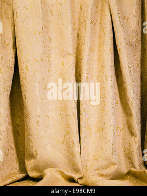 Rideaux suspendus de l'or avec un motif damassé luxueux de feuilles d'acanthe brillant pour un élégant décor intérieur Banque D'Images