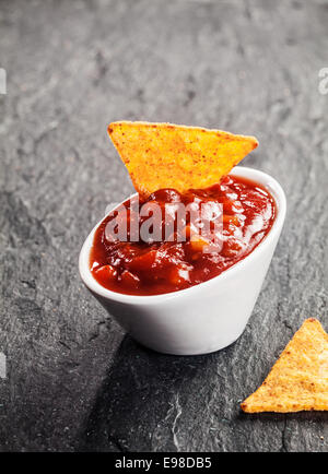 La tomate et piment épicé salsa trempette dans un petit bol en céramique blanche avec un totilla de maïs pour un apéritif ou un en-cas savoureux salé Banque D'Images