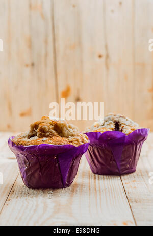 Deux des petits muffins en bonne santé avec du muesli et des écrous dans des gobelets en papier violet coloré pour un petit déjeuner sain ou teatime snack Banque D'Images