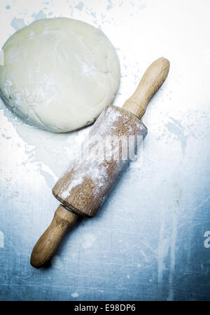 Vue de dessus d'un rouleau à pâtisserie en bois et avec la pâte de farine de boulangerie éparpillés sur une surface dans les tons bleus au cours de la préparation de la maison, pizza, biscuits, ou des biscuits Banque D'Images