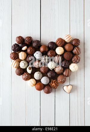 Forme de coeur fait avec divers types de truffes au chocolat sur une table en bois blanc Banque D'Images