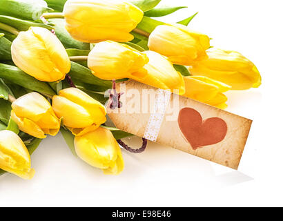 Vintage de étiquette en papier avec un cœur rouge sur un bouquet de tulipes jaunes assez frais sur un fond blanc Banque D'Images