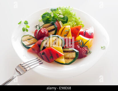 Veggie Cuisine végétarienne et végétalienne saine des légumes frais en dés rôties y compris baby marrow, tomate et poivrons doux garni d'herbes et de laitue verte à froufrous Banque D'Images