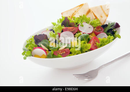 Mélange de salade de fruits frais et de pain fraîchement cuit au four avec des légumes verts à salade, radis, poivrons tomates amd sur un fond blanc Banque D'Images