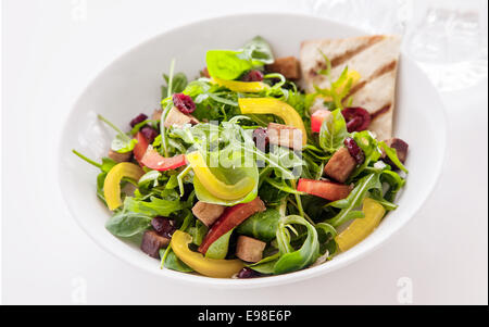 Bol de fusée colorés et salade d'herbes fraîches avec tomates et poivrons doux servi avec des portions de pain rôti cripsy pour un repas végétarien en bonne santé Banque D'Images