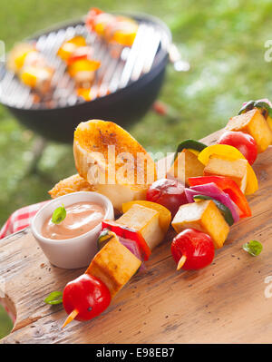 Brochettes de légumes et tofu fumé servi avec des tranches de pain baguette grillées et sauce sur une table de pique-nique en plein air à un barbecue d'été Banque D'Images