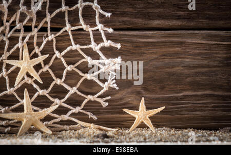 Contexte nautique avec étoile de mer et motif de losange filet de pêche sur des planches de bois avec un motif en similibois distinctif sur le sable de plage frais avec copyspace Banque D'Images