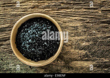 Un bol en bois rempli de lave hawaïens des cristaux de sel, un sel de mer de couleur noire par la lave volcanique et mélangé à du charbon désactivé , utilisé comme revêtement décoratif en cuisine épices et condiments Banque D'Images