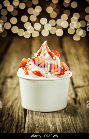 Fraise mûre, frais et sain sur un pot de yogourt glacé à la crème avec une pincée de sucre décoratif pearls pour vous traiter d'été contre un bokeh de lumières scintillantes Banque D'Images