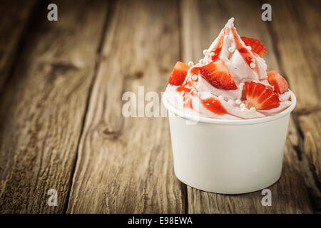 Fruits rouges fraises tropicales et glace vanille Crème Yaourt congelé pour une boisson fraîche dans un dessert d'été à remous à emporter sur une vieille table en bois rustique avec copyspace Banque D'Images