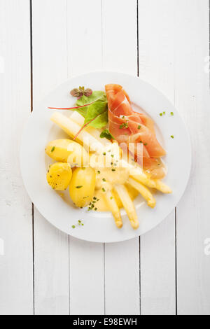 Les asperges et jambon de Parme italien ou du prosciutto avec mayonnaise servi avec des pommes de terre bouillies bébé pour un délicieux repas d'été froide, vue aérienne sur la table en bois blanc avec copyspace Banque D'Images