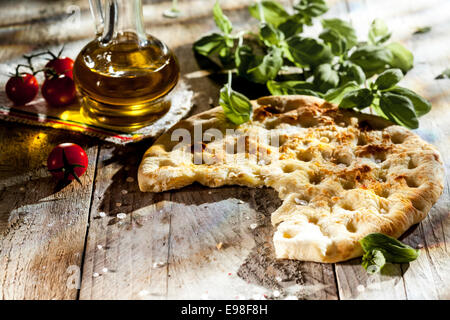 Focaccia italienne traditionnelle du pain, un pain plat salé cuit à partir de pâte de blé dur assaisonné d'herbes fraîches et d'huile d'olive sur une table en bois rustique Banque D'Images