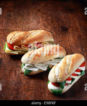 Baguettes d'or croustillant végétarien frais rempli d'un assortiment de fromage, basilic, roquette et tomate organisé sur un restaurant en bois comptoir pour une collation santé Banque D'Images