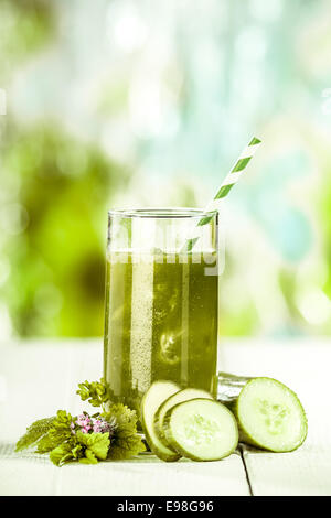 Grand Verre de plats fraîchement préparés et de mélanges de jus de légumes frais et sain avec des concombres sur une table en bois blanc à l'extérieur dans un jardin d'été Banque D'Images