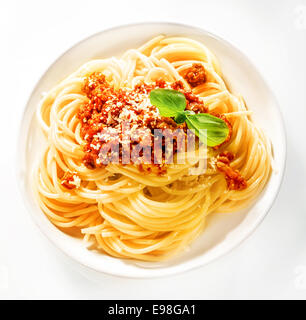 Au service de l'Italien spaghetti avec sauce tomate et viande bovine saupoudré de parmesan râpé et garnir de feuilles de basilic frais, vue de dessus Banque D'Images