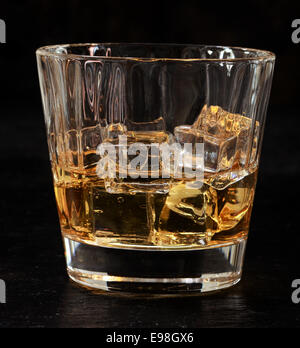 Verre de whiskey on the rocks servi bien frais sur des glaçons pour une boisson rafraîchissante au bar, vue rapprochée sur noir Banque D'Images