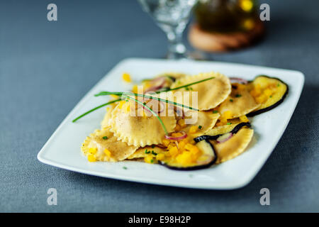 Ravioli italien végétarien pâtes aux tranches de rôti ou grillé ou l'aubergine aubergine servi sur une plaque carrée moderne garni Banque D'Images