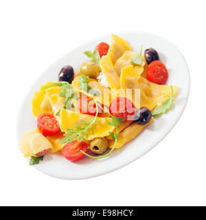 Raviolis italiens colorés avec salade de tomates fraîches, de fusée ou de feuilles de roquette, et d'olives noires et vertes pour un savoureux hors-d'isolated on white Banque D'Images