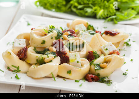 Nouilles pâtes tortellini italien farci à la feta, le basilic et les pignons de pin servi avec une salade de légumes verts Banque D'Images