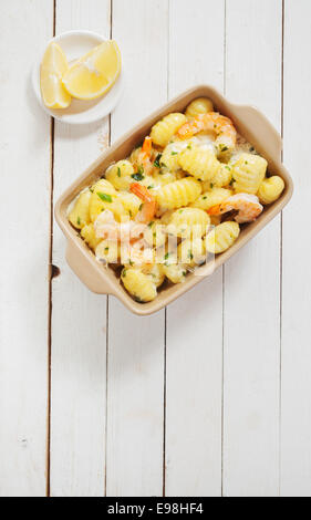 Servi avec des gnocchi crevettes roses décortiquées assaisonné d'herbes fraîches hachées et de citron sur une table de jardin en bois blanc, rustique, vue du dessus avec copyspace Banque D'Images