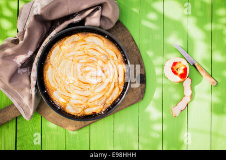 Golden Delicious apple pie maison vue d'en haut dans un plat à four sur une table de jardin en bois vert tacheté dans la lumière du soleil pour se détendre autour d'un repas d'été et dessert Banque D'Images