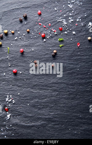 Assortiment ensemble poivre et sel dispersées sur un fond d'ardoise naturelle foncé texturé avec copyspace Banque D'Images