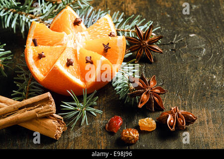 L'orange de Décoration Noël encore la vie avec une coupe fresh orange niché dans une branche de pin avec le bâton de cannelle, étoiles abise et écrous sur un fond en bois rustique avec copyspace pour votre message d'accueil Banque D'Images