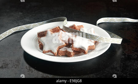 Assiette de cookies de Noël traditionnel en forme de vitrage blanc star avec un ruban d'argent de décoration pour une fête historique Banque D'Images