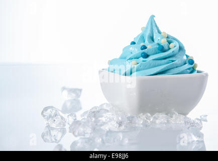 Délicieux Yogourt glacé de couleur blanche sur le bol avec des cubes de glace sur les côtés. Isolé sur blanc. Banque D'Images