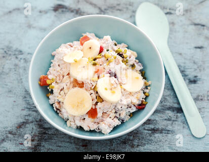 Délicieux bol de muesli sain surmonté de fruits et noix, vu du dessus sur un comptoir en pierre Banque D'Images