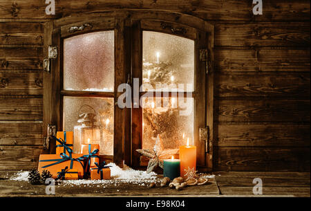 Fêtes de Noël en bois avec vitre de cabine d'un emballage-cadeau coloré  orange présente, brûler des bougies et des décorations en hiver la neige et  un aperçu d'un arbre de Noël décoré