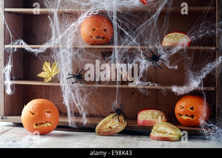 Garde-manger d'Halloween Spider web étagères couvertes de ramper avec de grandes araignées noir et orange jack-o-lanternes avec visages effrayants et une chauve-souris volant au-dessus Banque D'Images