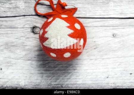 Boule de Noël rouge décoré d'un arbre et Polka Dots accroché contre un mur en bois patiné dans un concept de fond de Noël rustique Banque D'Images