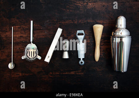 Ensemble d'accessoires de bar ou au pub avec un martini shaker disposés dans une ligne soignée sur fond noir Banque D'Images