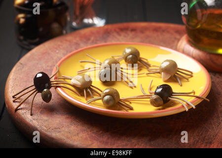 Crawly Creepy Halloween araignées comestibles fabriqués à partir de guéri olives vertes et noires avec jambes spaghetti italien sur une table à une fête d'Halloween pour les entrées ou de faveurs pour trick-ot-traiter Banque D'Images