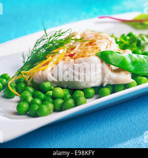 Grillée ou filet de poisson cuit au four garnie de zestes de citron et servi sur une plaque avec des petits pois, pois mange-tout ou sugarsnap, et frais Banque D'Images