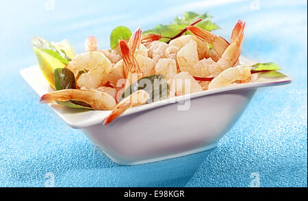 Bol de crevettes grillées délicieuses queues de crevettes ou garni d'épinards et de citron sur un fond bleu turquoise Banque D'Images