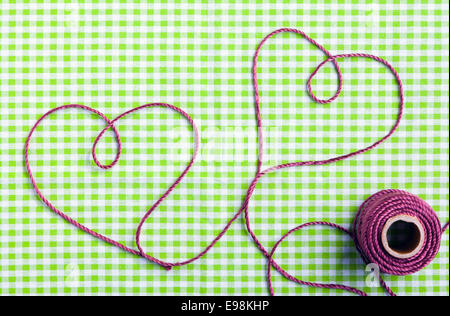 Coeur dessiné avec purple thread via un tag sur un motif de tissu à carreaux Banque D'Images