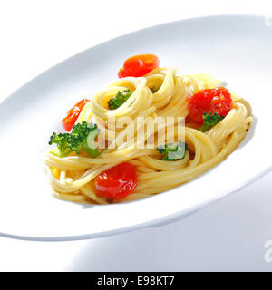 Une plaque de brocoli spaghetti préparé prêt pour servir garni de tomates et basilic Banque D'Images